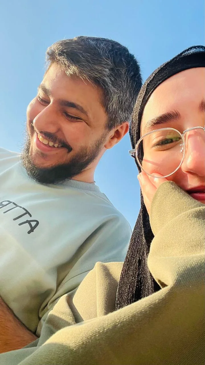 A selfie taken from below against a clear blue sky, both of us laughing.