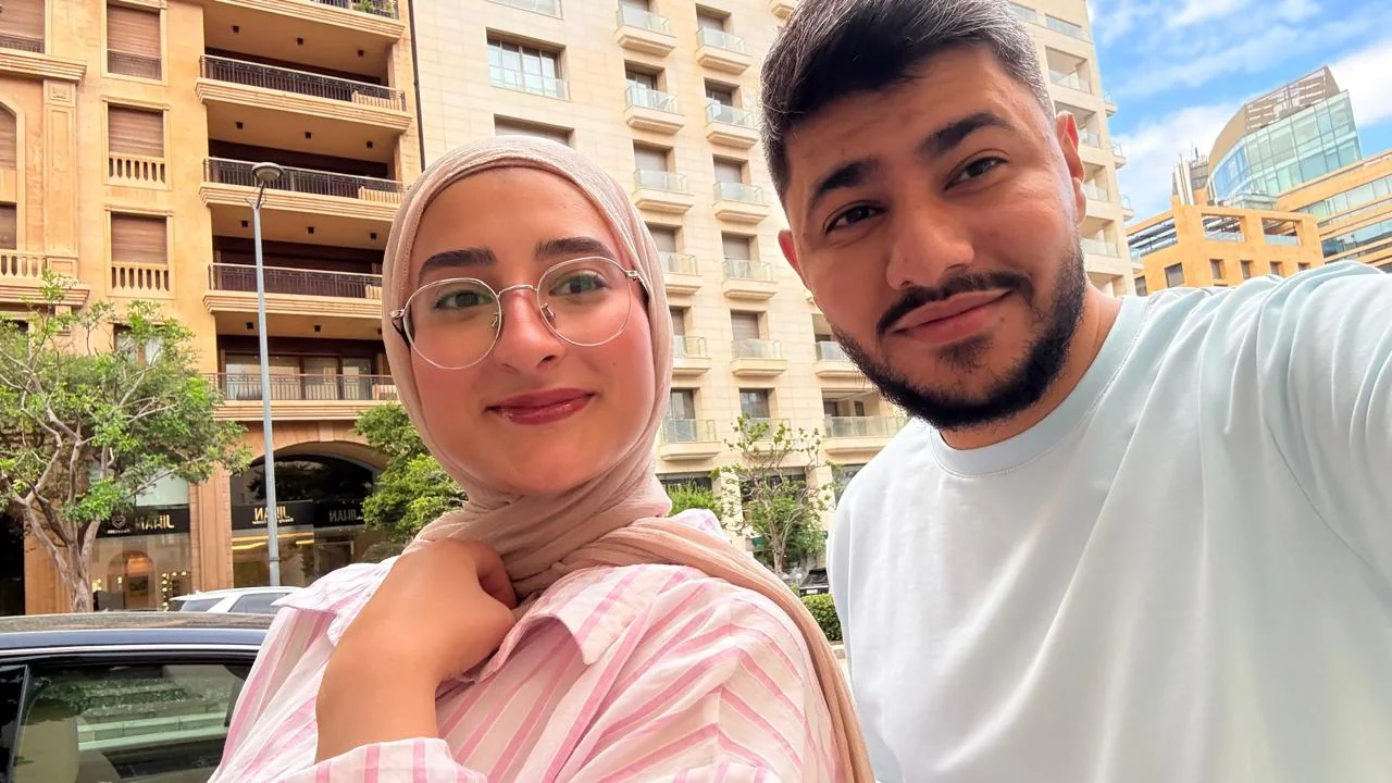 A selfie of the two of us on a city street, with stone buildings and blue sky behind.