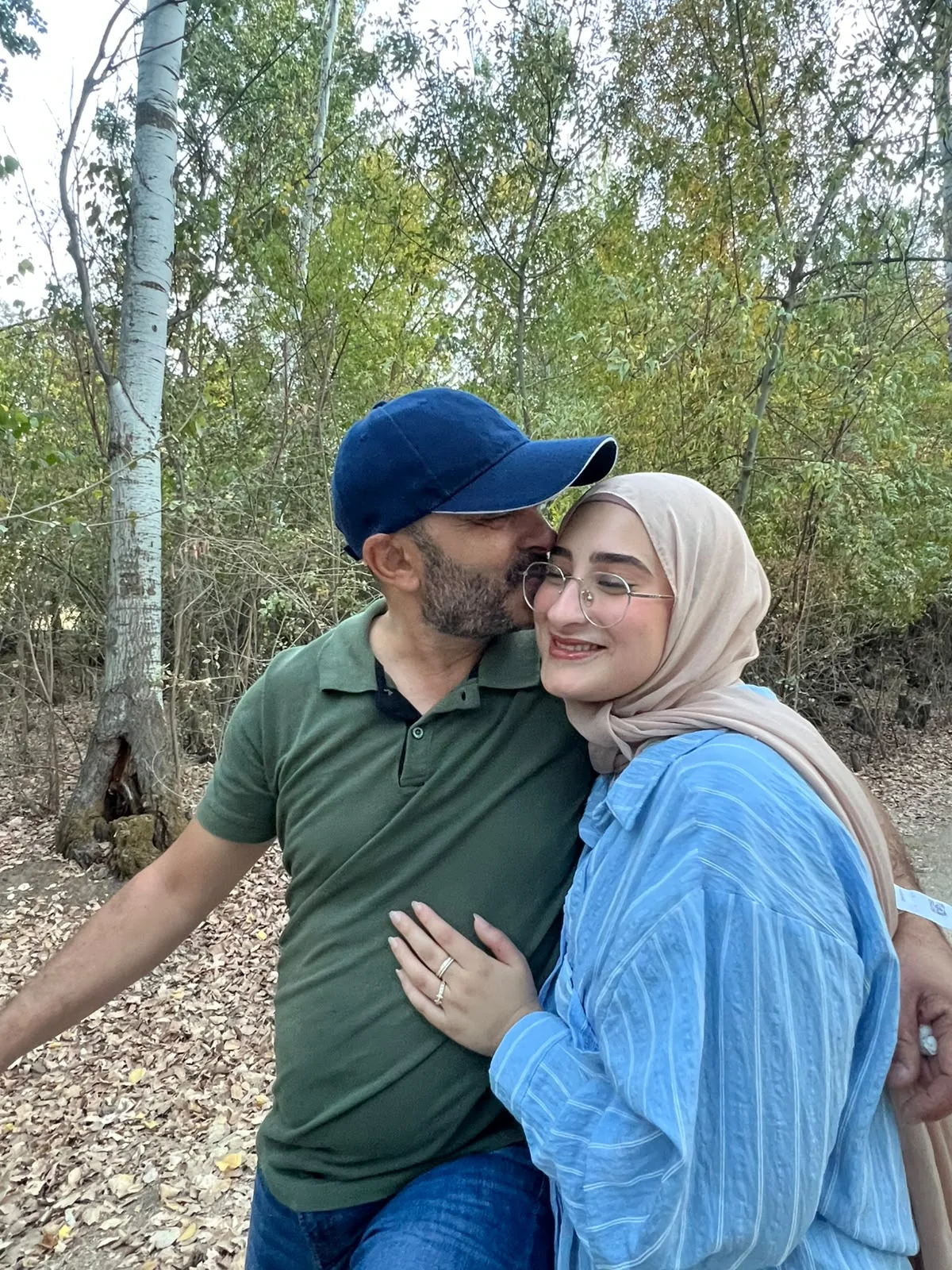 A kiss on the cheek for a smiling Fatima, among the trees.
