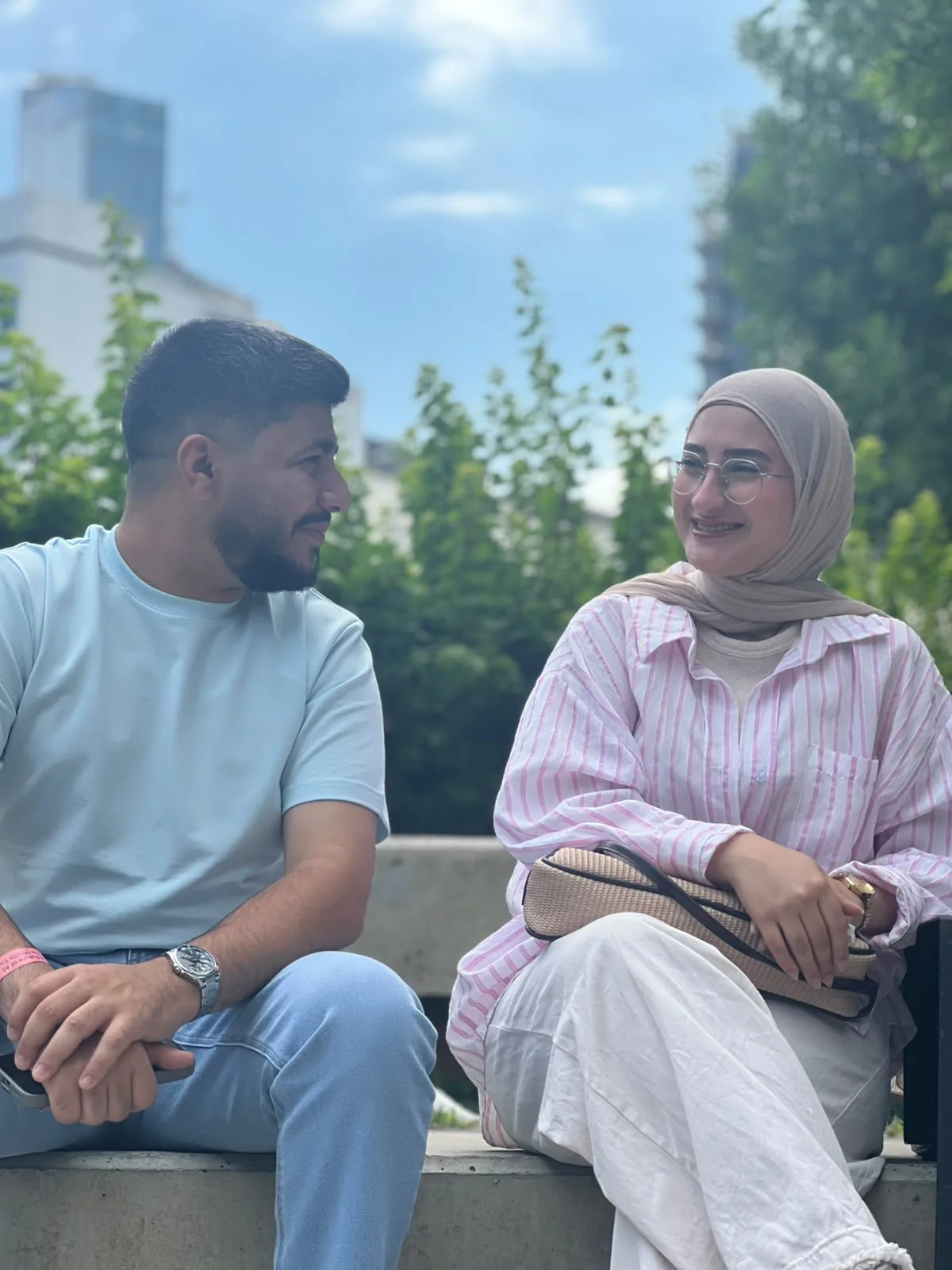 The two of us sitting on a low wall, turned toward each other and smiling.